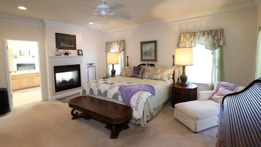 Traditional bedroom with a fireplace, plush bed, and cozy seating area.