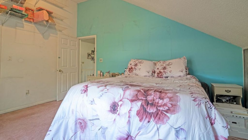 Bedroom with floral bedding and a turquoise accent wall.