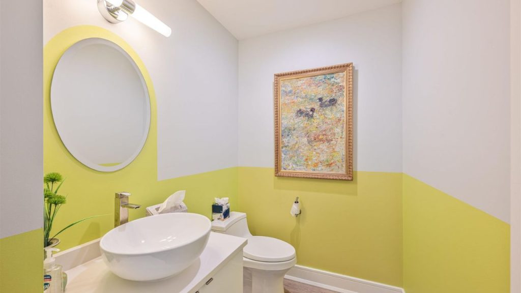 A modern powder room with two-tone walls, a vessel sink, and abstract artwork.