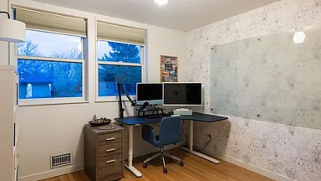 Modern home office with dual monitors, a black desk, and a large whiteboard.