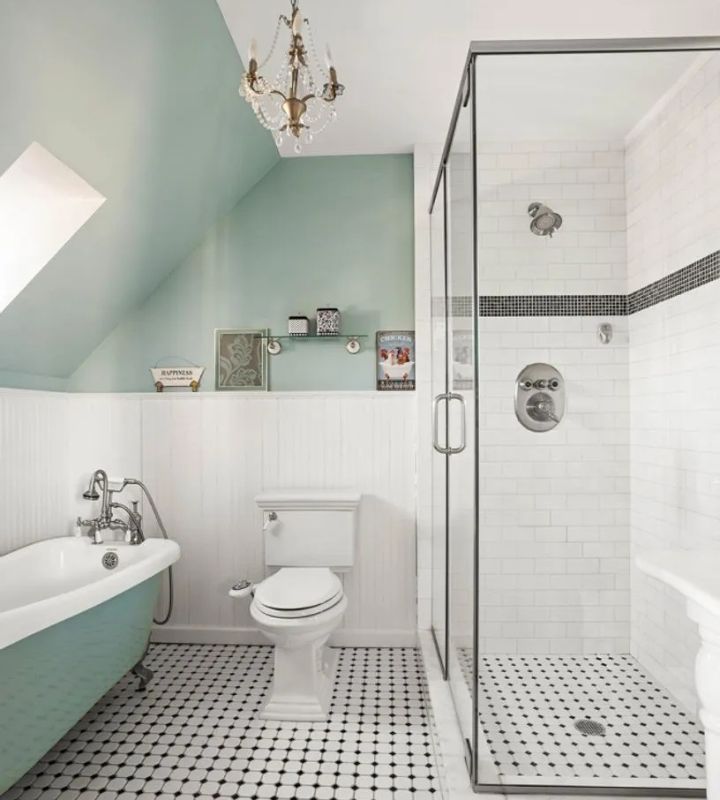 Vintage-style bathroom with a clawfoot tub, glass shower, and chandelier.