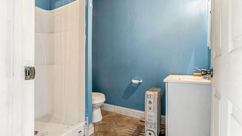 Small bathroom with blue walls, a walk-in shower, and a white vanity.