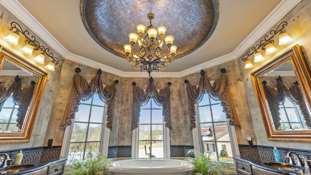 Elegant vintage-style bathroom with a freestanding tub, gold accents, and a grand chandelier.