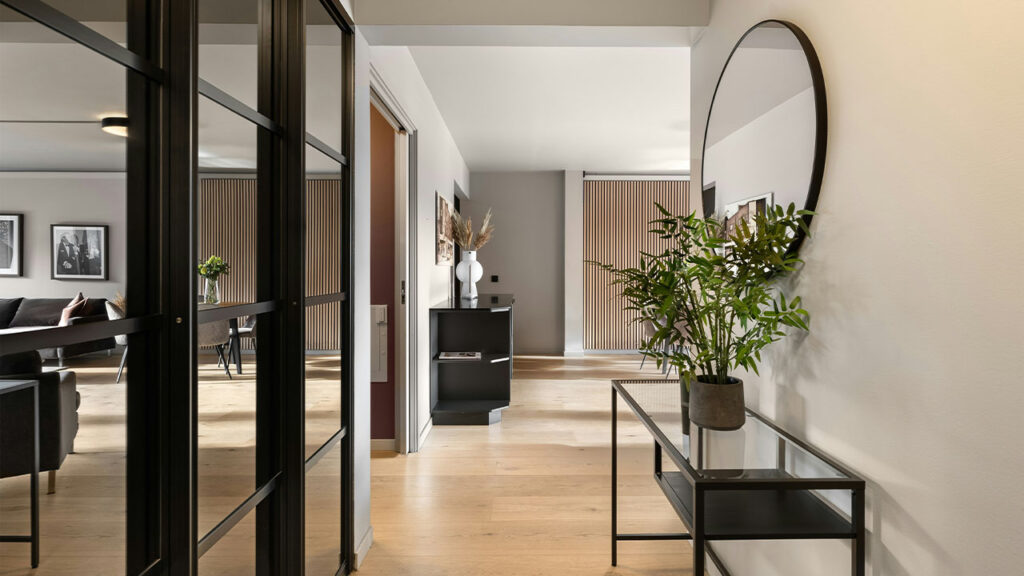 A hallway with a mirror and a table with a plant on it