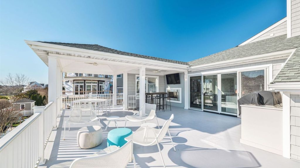 A bright rooftop terrace with lounge seating, a fireplace, and a barbecue.