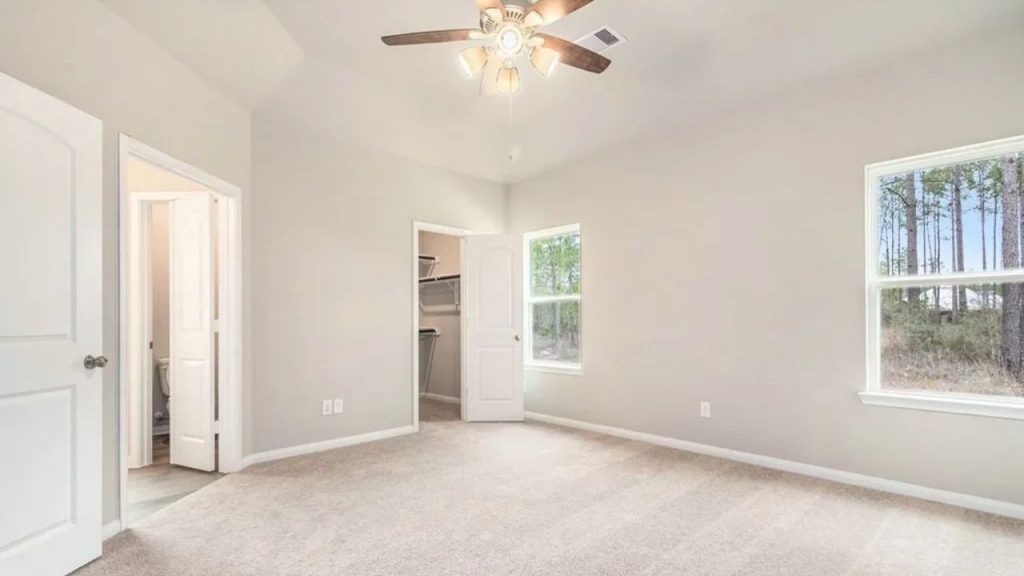 Spacious bedroom with a ceiling fan, walk-in closet, and large windows.