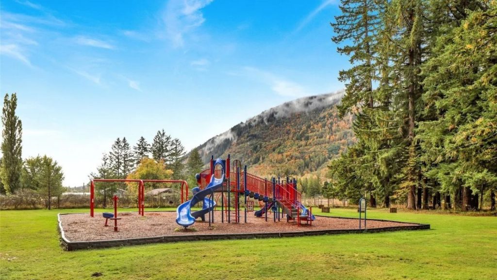 Colorful playground set in a scenic valley with mountain views.