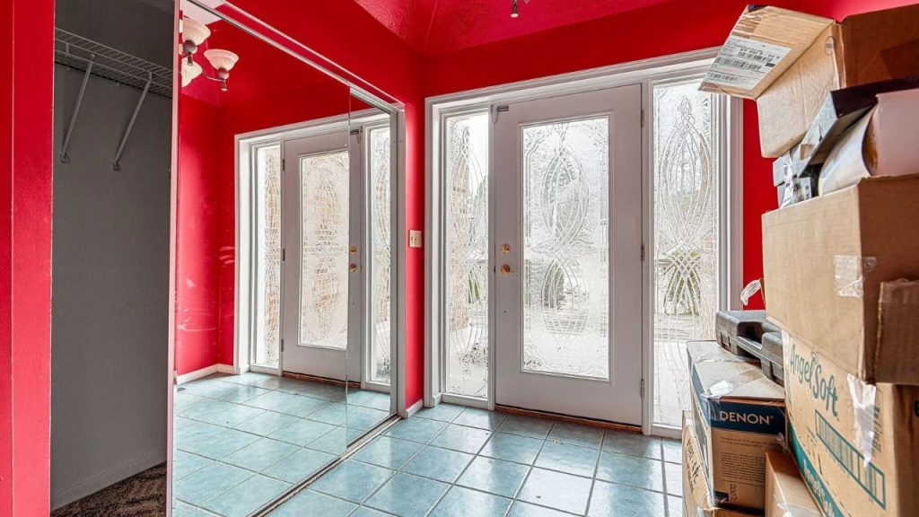 Red-walled entryway with glass-paneled doors and mirrored closet.