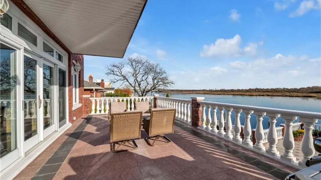 Spacious waterfront terrace with outdoor seating, balustrade railings, and scenic views.
