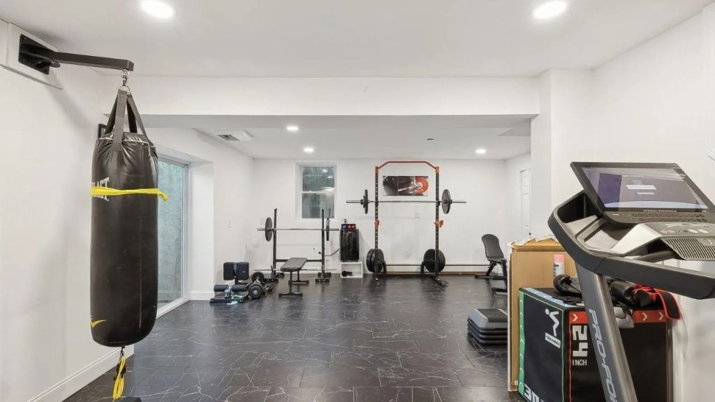 Home gym with a punching bag, squat rack, treadmill, and free weights.