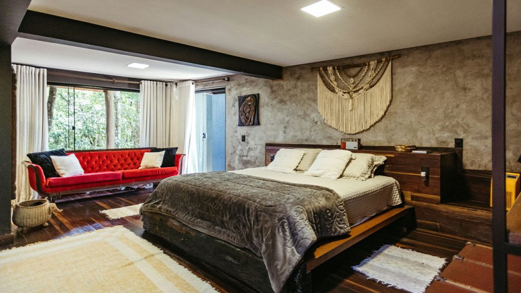 A bedroom with a large bed and a red couch