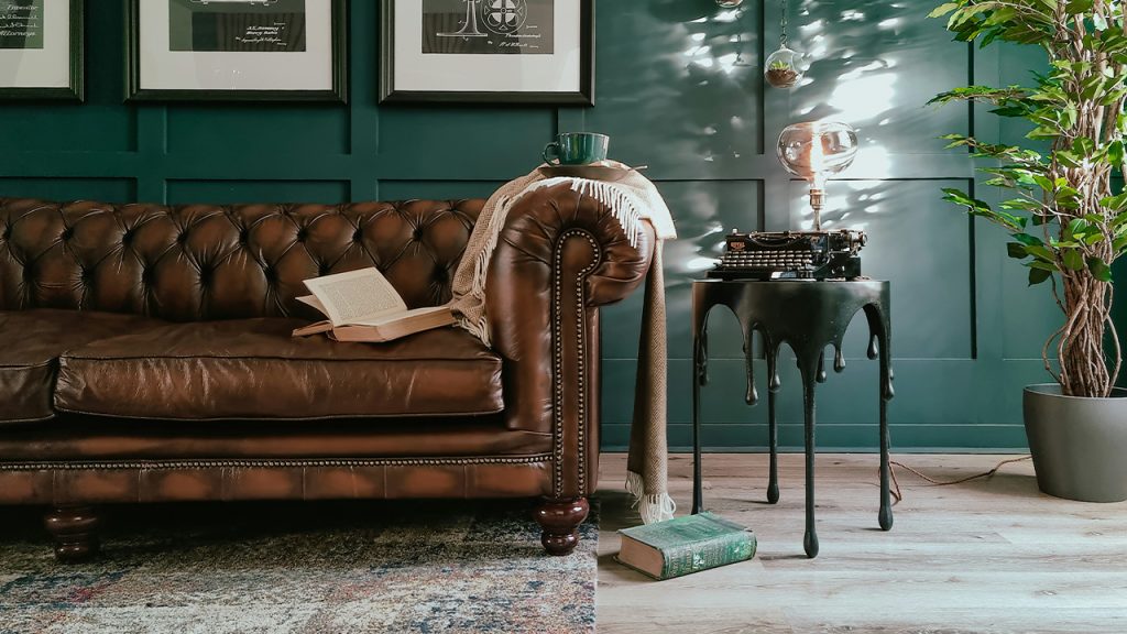 A vintage leather Chesterfield sofa in a room with vintage books, coffee, and an upcycled antique typewriter lamp.