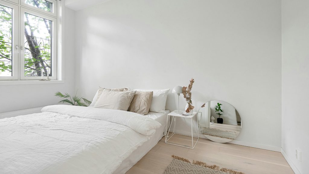 A bedroom with a white bed and a large window