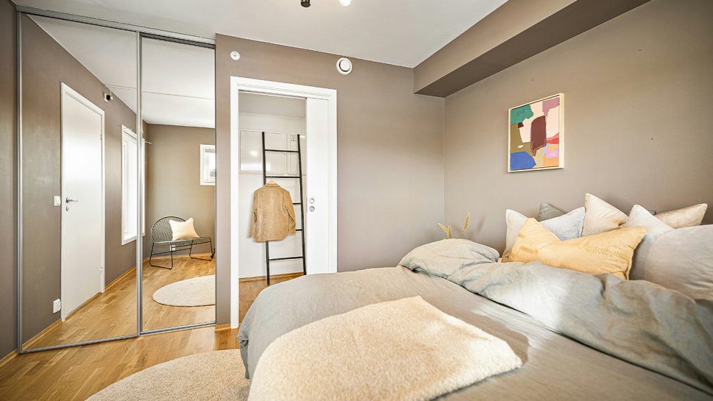 A bed room with a neatly made bed and a mirror