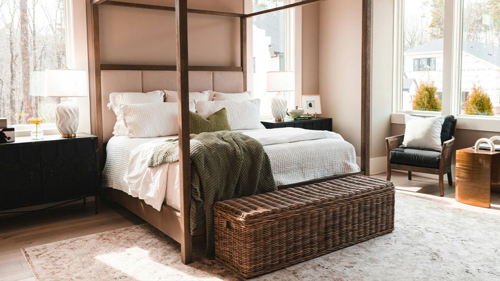 a bedroom with a four poster bed and a wicker trunk