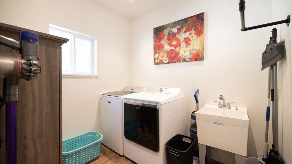 Bright and organized laundry room with washer, dryer, and utility sink.