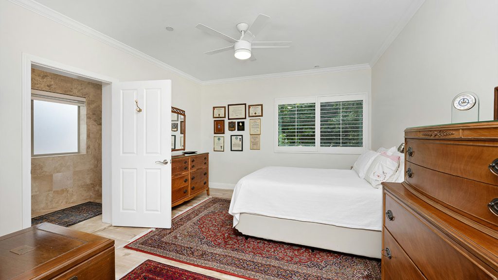 A bedroom with a bed, dresser, and a mirror