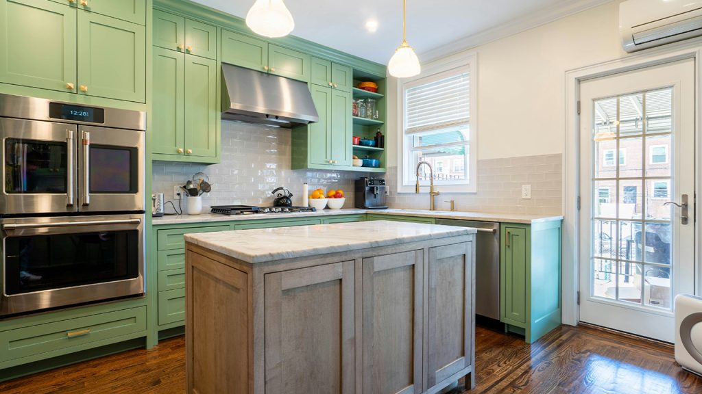 a kitchen with green cabinets and stainless steel appliances