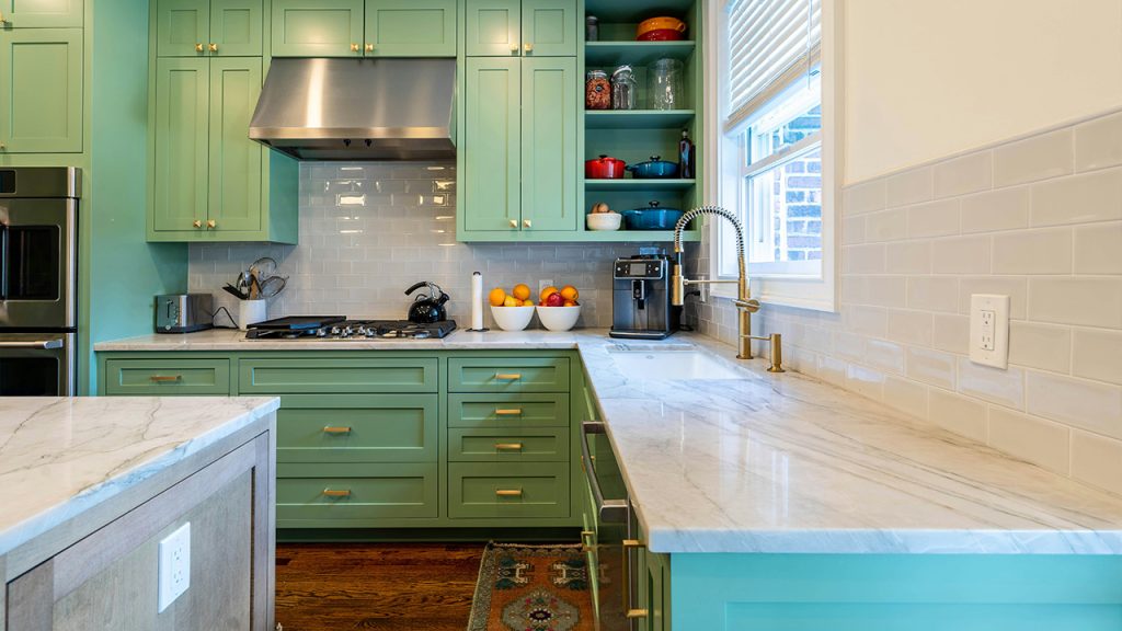 a kitchen with green cabinets and marble counter tops