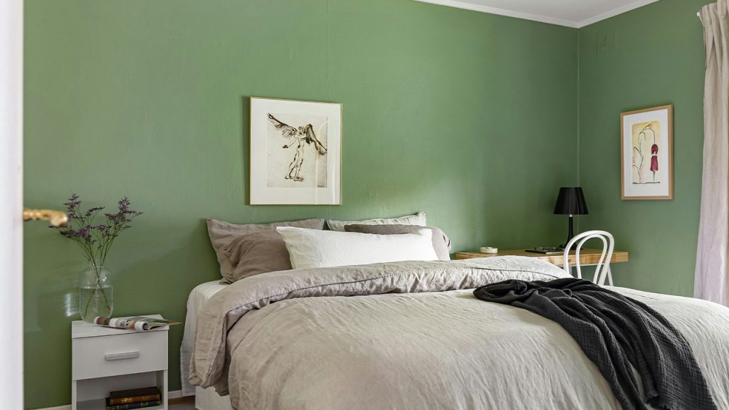 A bedroom with green walls and a white bed