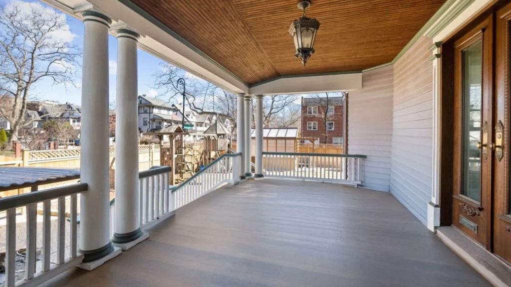 Spacious front porch with columns, wood ceiling, and glass-paneled doors.