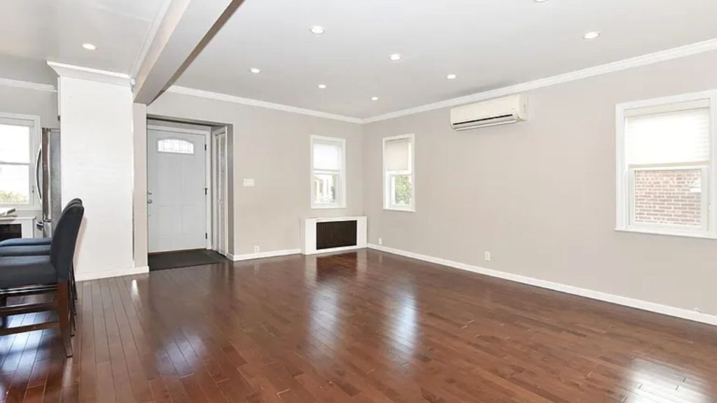 Spacious living room with hardwood floors, recessed lighting, and large windows.