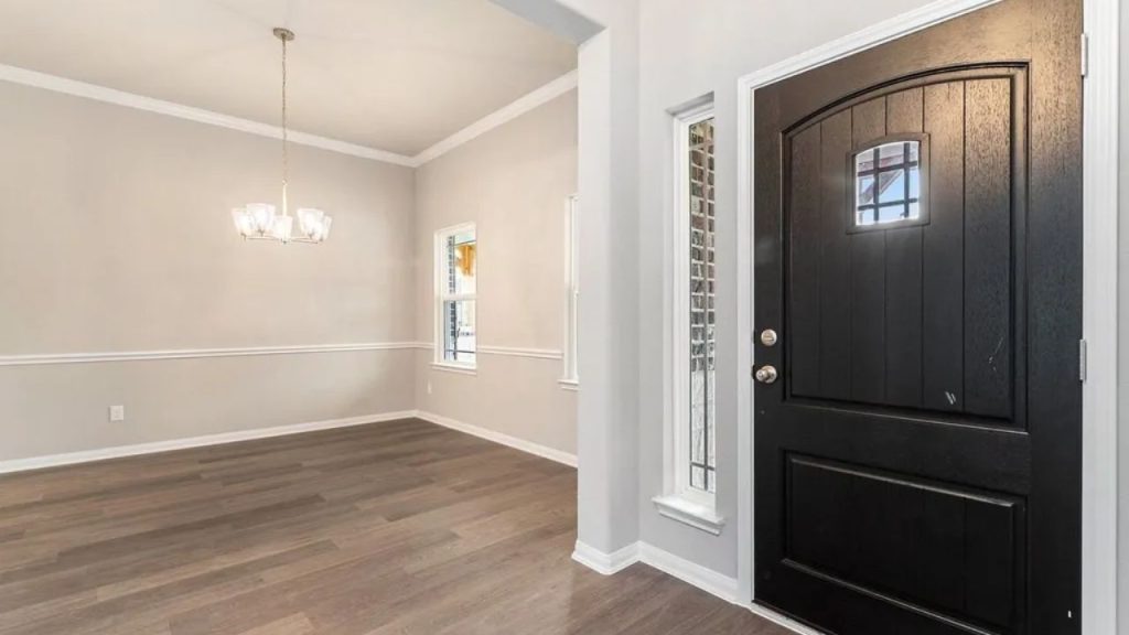 Entryway with a black front door, wood-like flooring, a chandelier, and tall windows.