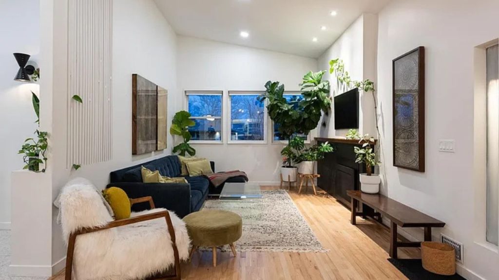 Cozy living room with a navy sofa, faux fur chair, large plants, and warm wood accents.