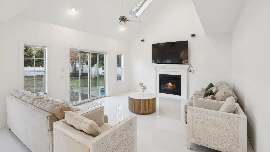 Bright living room with a fireplace, skylight, and neutral-toned seating.