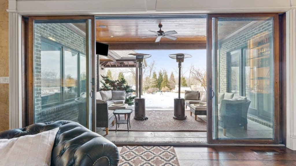 Indoor-outdoor space with sliding glass doors, patio seating, and heaters.