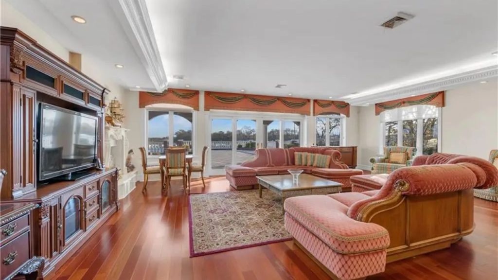 Luxurious living room with classic décor, hardwood flooring, and large windows leading to an outdoor terrace.