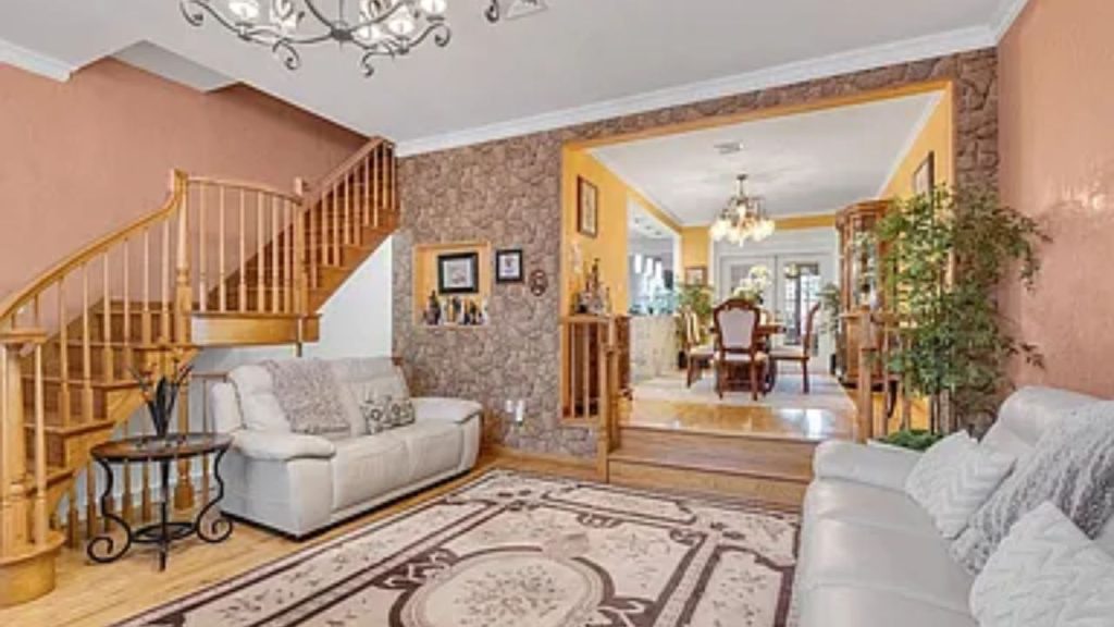 Living room with a curved staircase leading to a grand dining area.