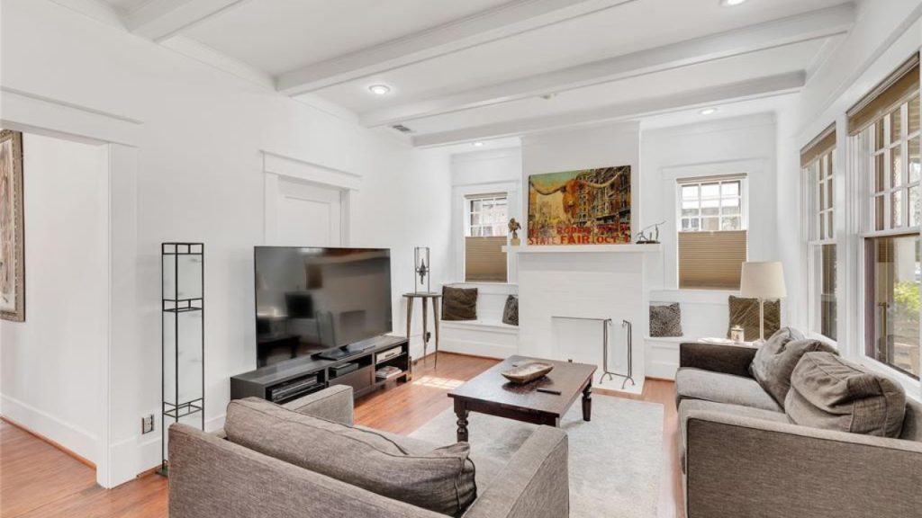 Spacious living room with white walls, wood floors, a fireplace, and gray sofas.