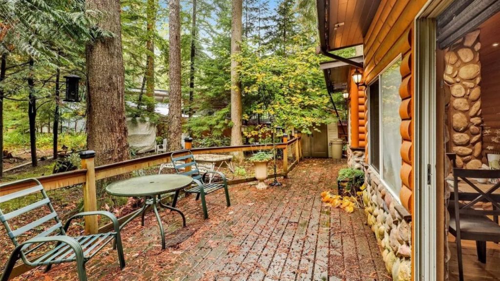 Brick patio with outdoor seating, nestled in a wooded setting beside a log cabin.