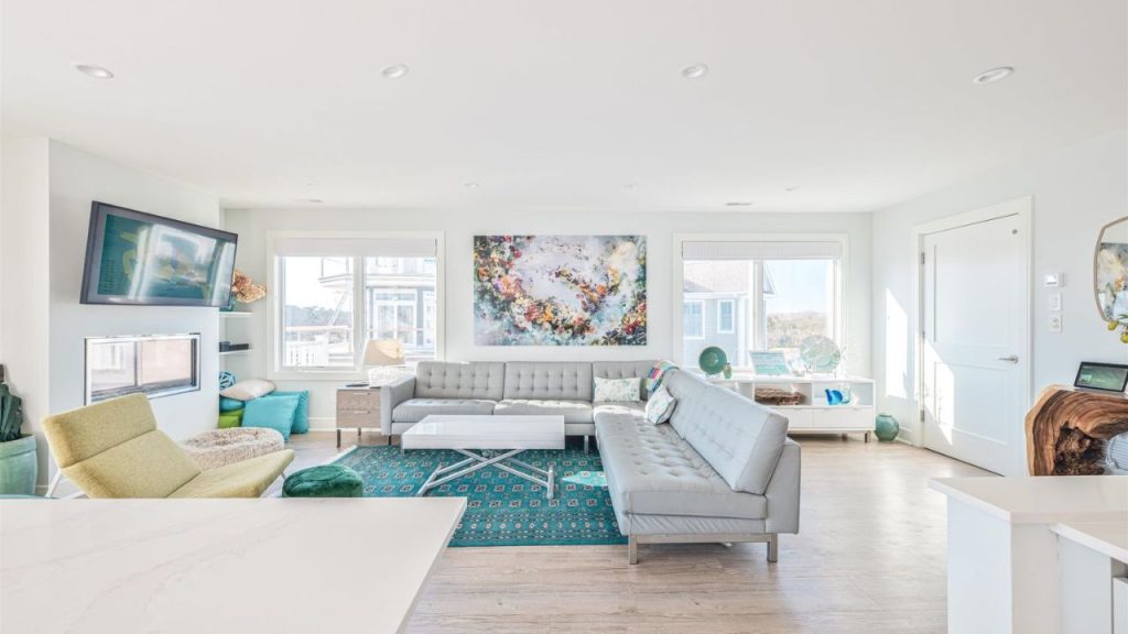 A bright, modern living room with large windows, a fireplace, and contemporary décor.