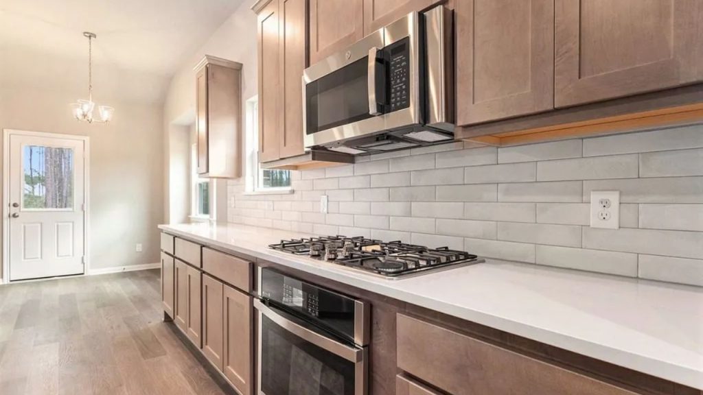 Modern kitchen with wooden cabinets, stainless steel appliances, and a gas cooktop on a white countertop.
