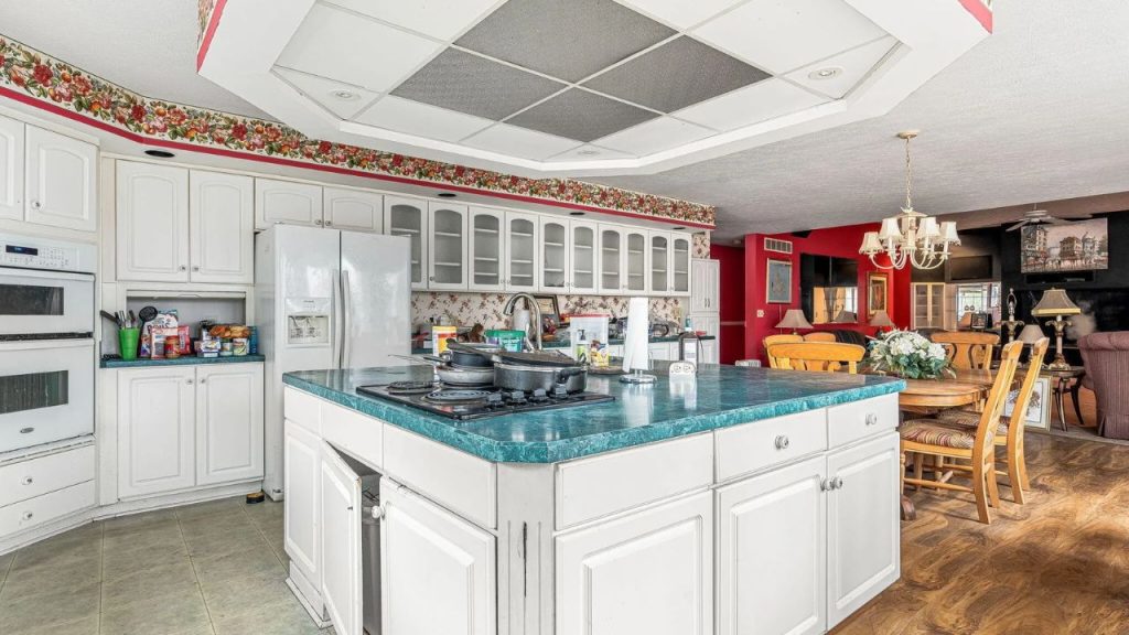 Spacious traditional kitchen with white cabinets, green countertops, and a center island with a stovetop.
