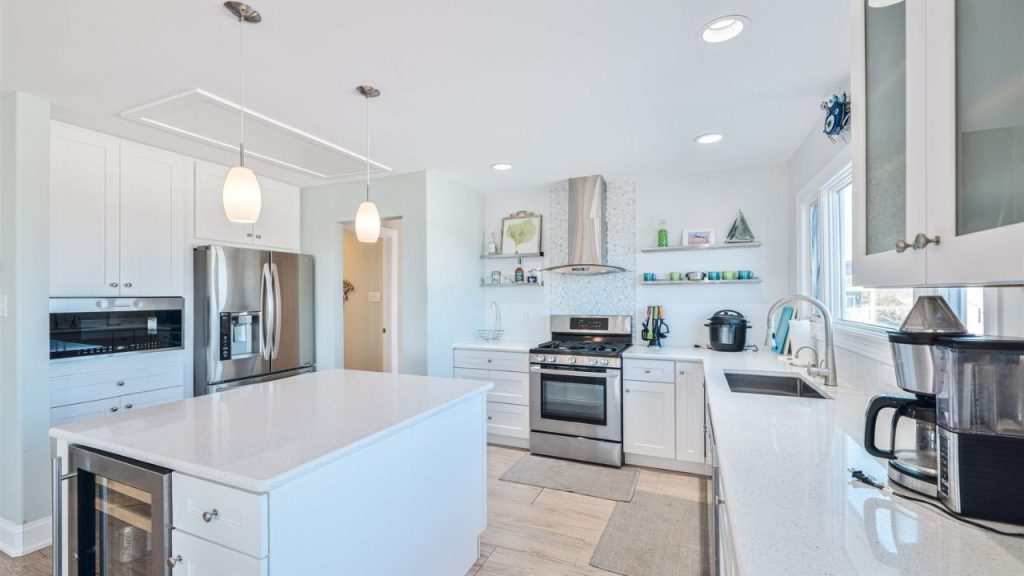 A bright, modern kitchen with white cabinetry, stainless-steel appliances, and an island.