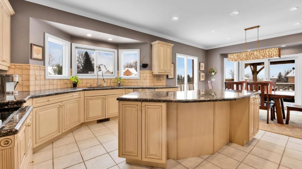 Large kitchen with a central island, granite countertops, and dining area with outdoor views.
