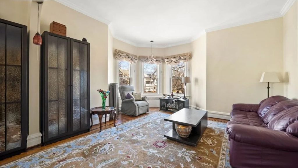 Elegant living room with a bay window, leather sofa, and glass-paneled cabinets.