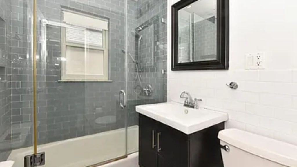 Modern bathroom with a glass-enclosed shower, dark vanity, and white subway tile walls.
