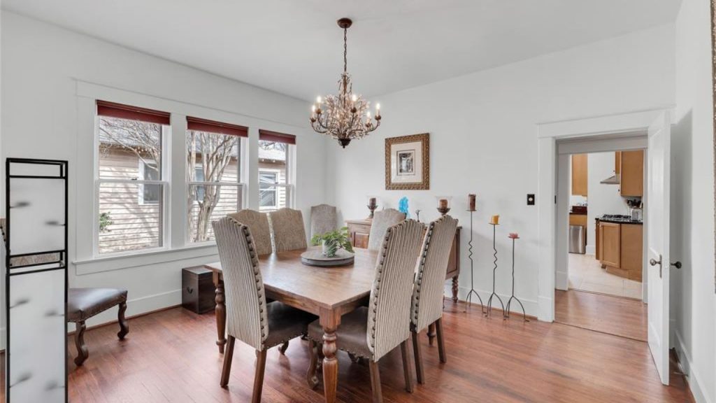 Bright dining room with wood flooring, large windows, and a chandelier.