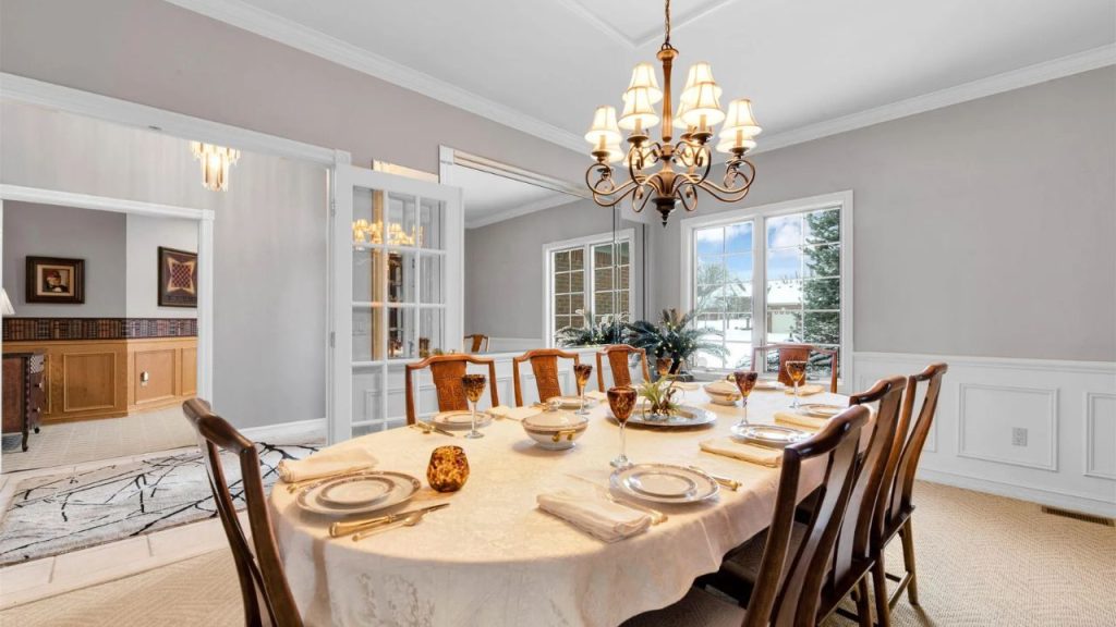 Formal dining room with a set table, chandelier, and large windows.