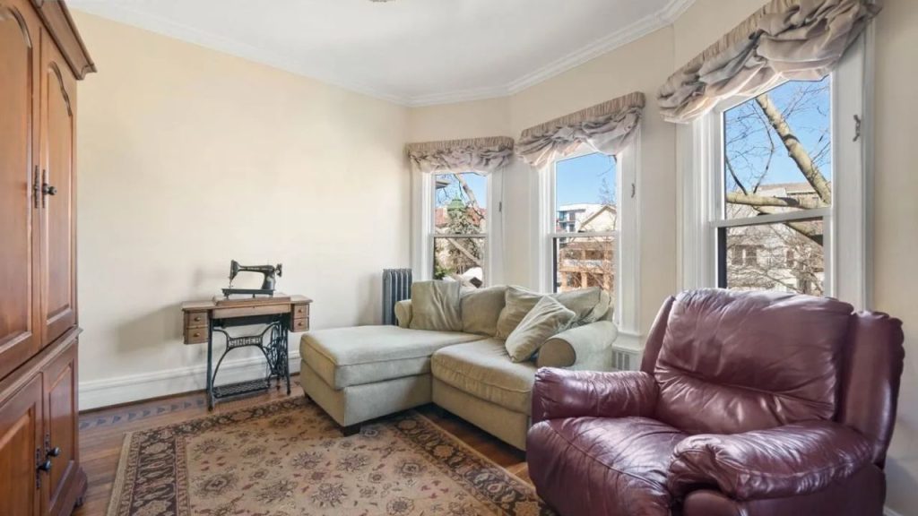 Bright sitting room with a chaise lounge, leather armchair, and vintage sewing table.