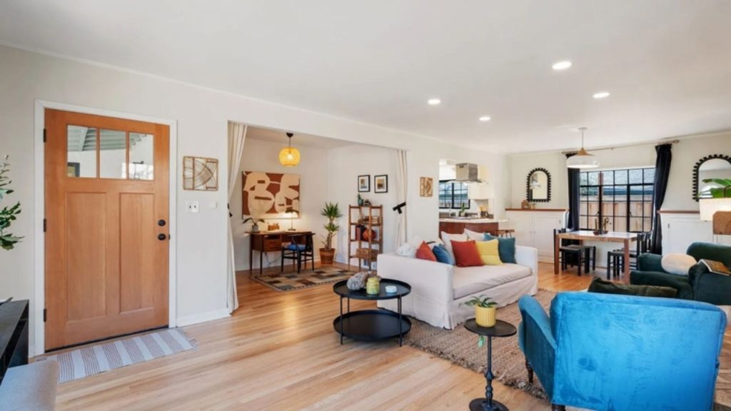 Bright living room with wooden floors, colorful seating, and an open dining area.