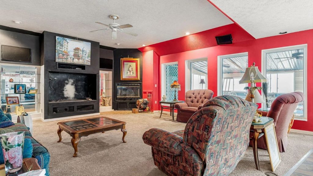 Cozy living room with red walls, a black entertainment center, a fireplace, and patterned seating.