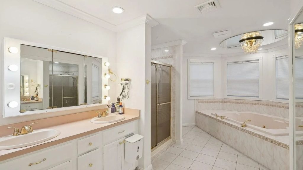 Spacious bathroom with a vanity, Hollywood-style mirror, soaking tub, and gold accents.