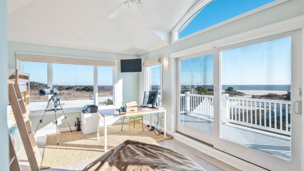 Bright home office with ocean views and a telescope by the window.
