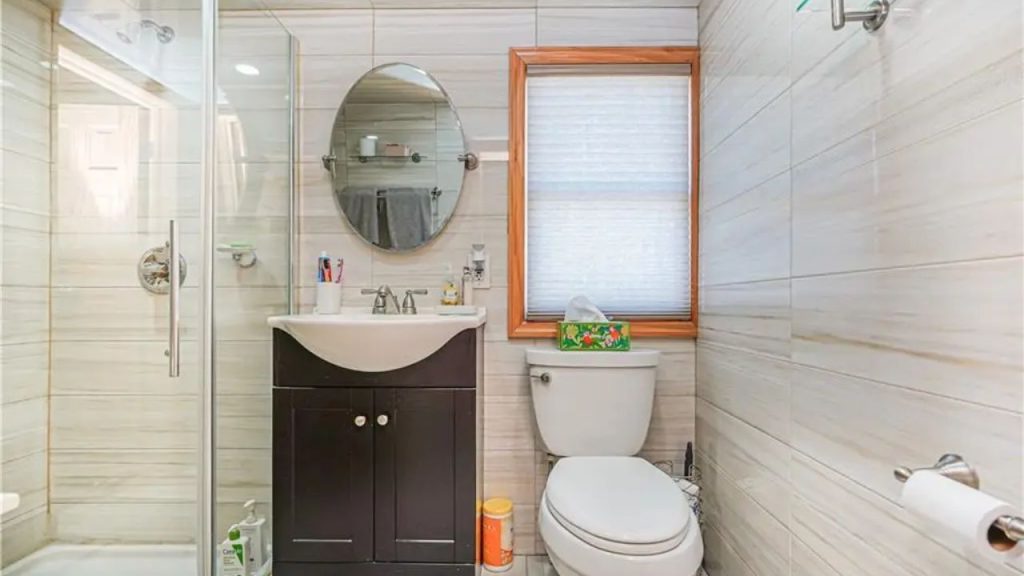 Elegant bathroom with a glass shower and wood-accented window.