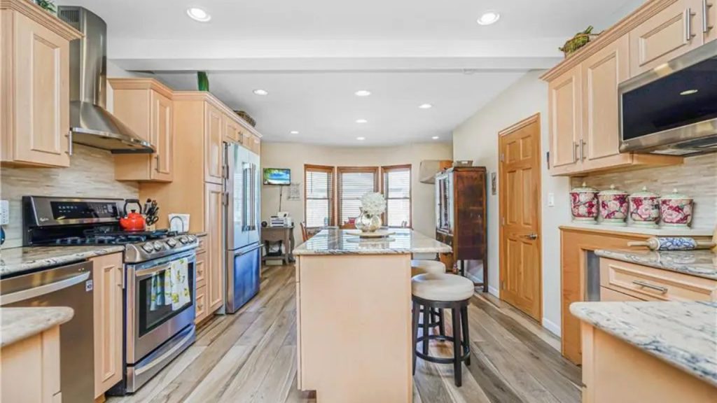Spacious kitchen with wood cabinetry, granite countertops, and a central island with barstools.